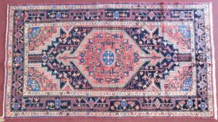 A Persian Toserkan rug, central double pendant medallion with repeating petal motifs on a rouge