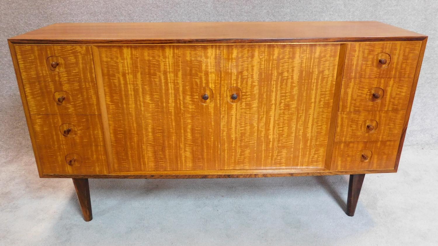 A Gordon Russell sideboard fitted drawers and cupboards on splayed supports, makers label to back.