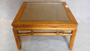 A Chinese style teak low table with inset rattan top and drop in glass section. 50x88x88cm