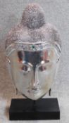 A decorative silvered buddha's head on stand. 60x29cm