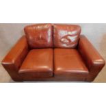 A Thomas Lloyd two seater leather sofa in tan leather. 87x155x97cm