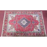 a large Persian rug, with a central double pendant medallion, on a rouge field with repeating floral