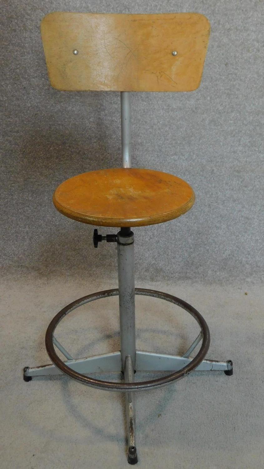 A vintage revolving adjustable industrial machinist's stool with laminated beech seat and back.