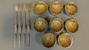 A set of eight scallop design silver plated salts with knives.