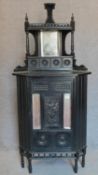 A late 19th century ebonised corner cabinet with mirrored back and carved panels in the aesthetic