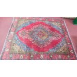 A Kirman style carpet, central double pendant medallion with repeating floral motifs on a rouge