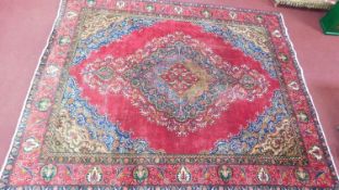 A Kirman style carpet, central double pendant medallion with repeating floral motifs on a rouge