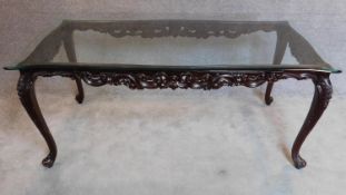 A Continental style mahogany dining table with shaped plate glass top on cabriole supports.