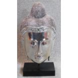 A decorative silvered buddha's head on stand. 60x29cm