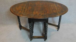 A Jacobean style carved oak drop flap dining table on bobbin turned supports. 76x135x92cm