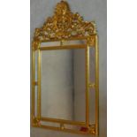 A carved giltwood wall mirror with mirrored panels and scrolling foliate cresting. 109x62cm