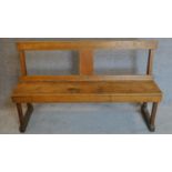 An oak panel seated bench on strethered end supports. 80x134cm