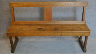 An oak panel seated bench on strethered end supports. 80x134cm