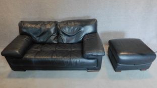 A black leather 2 seater sofa with buttoned seat and matching footstool. 75x179x98cm (sofa)