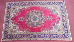 A Persian Tabriz carpet, central double pendant medallion on a rouge field within floral borders,