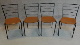 A set of four metal framed chairs with tan leather seats. H.82cm