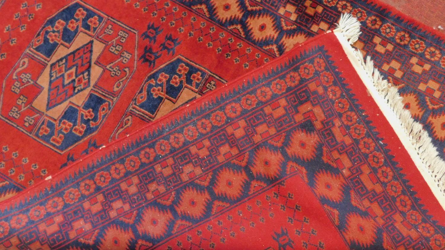 A Persian style rug with triple pendant medallions on a terracotta field surrounded by repeating - Image 3 of 4