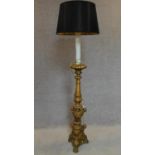 A carved giltwood floor standing standard lamp with carved cherub decoration on tripod carved paw