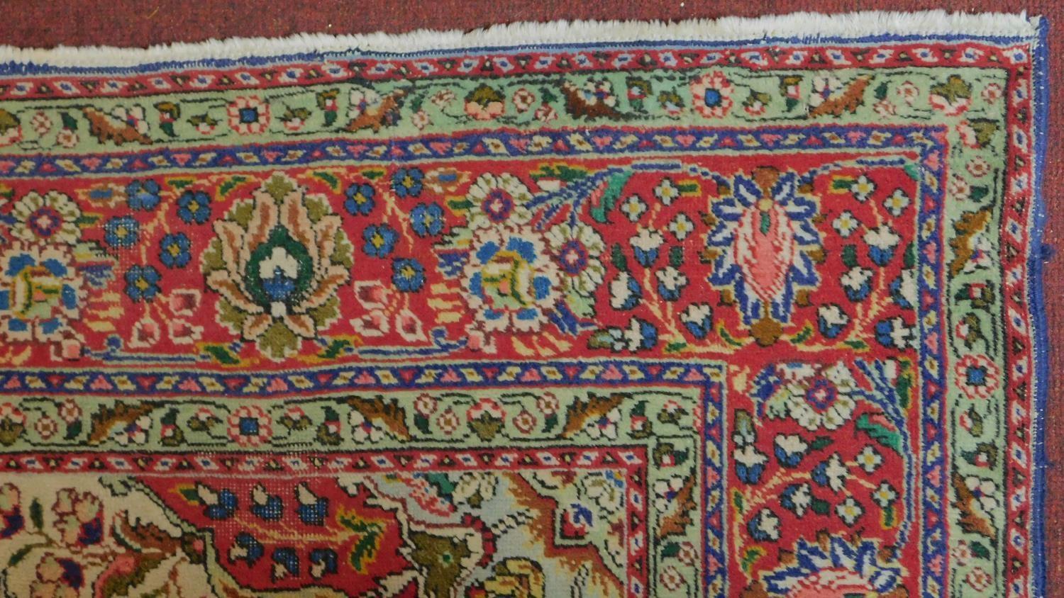 A Tabriz rug with central medallion and repeating floral motifs set on a predominantely rouge and - Image 2 of 4