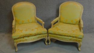 A pair of French style fauteuil with distressed painted frames in lemon floral upholstery. H.102cm