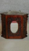 A small Victorian mahogany hanging wall cabinet with pierced carved decoration and mirrored door.