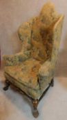A William and Mary style walnut framed tapestry covered arched back wing armchair on stretchered