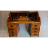 An American style teak roll top desk with fitted pigeon hole interior on pedestal bases fitted