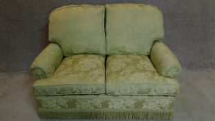 A two seater sofa in floral green upholstery. 97x145x80cm