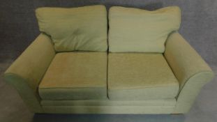 A two seater sofa in cream upholstery. 70x175x90cm