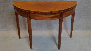 A Georgian mahogany and satinwood strung demi lune foldover top card table on square tapering