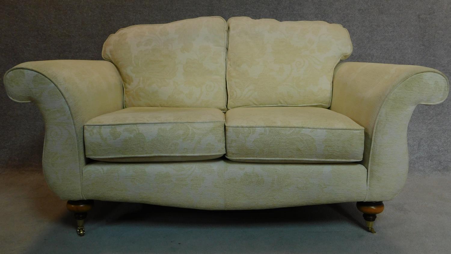 A two seater Victorian style sofa in beige floral upholstery and mahogany turned feet terminating in - Image 2 of 5