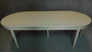 A white painted and decorated Georgian style extending dining table with three extra leaves,
