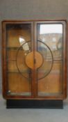 A Continental Art Deco walnut display cabinet with shaped glazed and panelled doors on ebonised