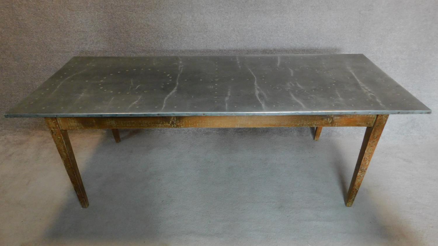 A 19th century pitch pine refectory dining table with studded zinc top on square tapering