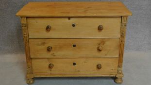 A 19th century Continental pine chest of drawers with carved side pilasters on turned bun feet.