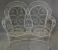 A wrought iron and painted two seater garden bench with shaped hooped twin backs. H.104 W.119cm