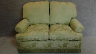 A two seater sofa upholstered in green floral upholstery. 90x145x87cm