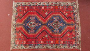 A shiraz Rug with twin geometric sapphire medallions on a red ground contained by geometric borders.