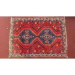 A shiraz Rug with twin geometric sapphire medallions on a red ground contained by geometric borders.