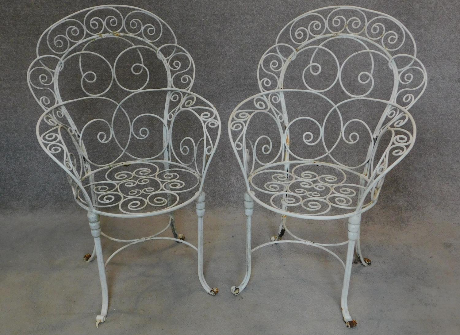 A pair of wrought iron and painted shaped back garden armchairs. H.104cm