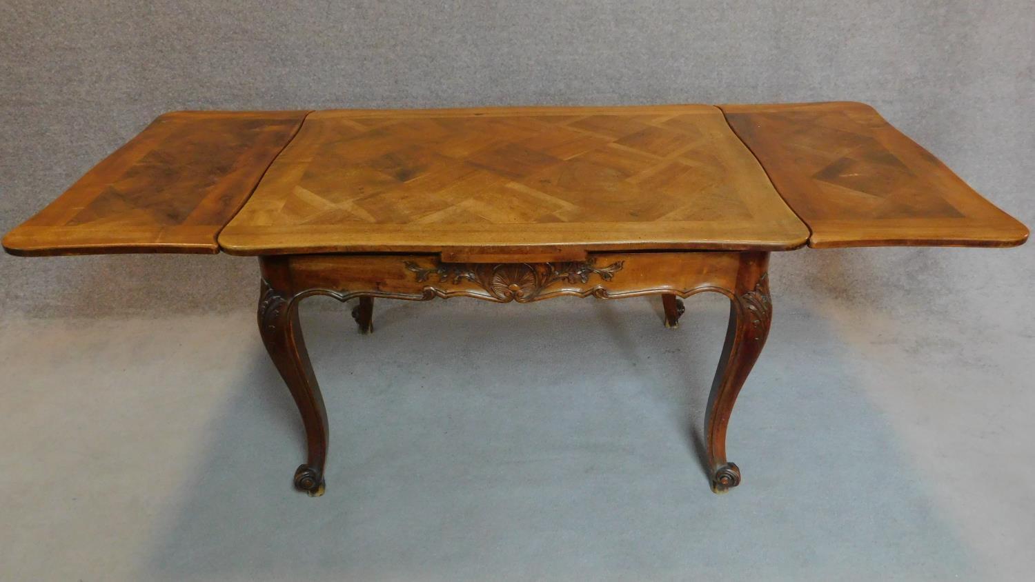 A French walnut draw leaf dining table with parquetry top on well carved base with cabriole