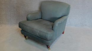 A Howard style upholstered armchair on mahogany turned tapering supports. H.88cm