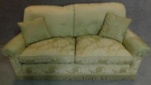 A two seater sofa in floral green upholstery. 77x188x85cm