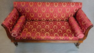 A William IV rosewood scroll end sofa in rouge and gold laurel wreath upholstery on turned fluted