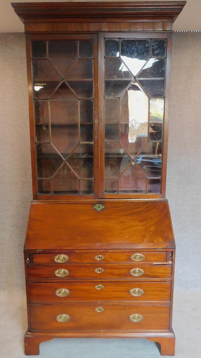 A Georgian mahogany bureau bookcase, the astragal glazed upper section above fall front revealing