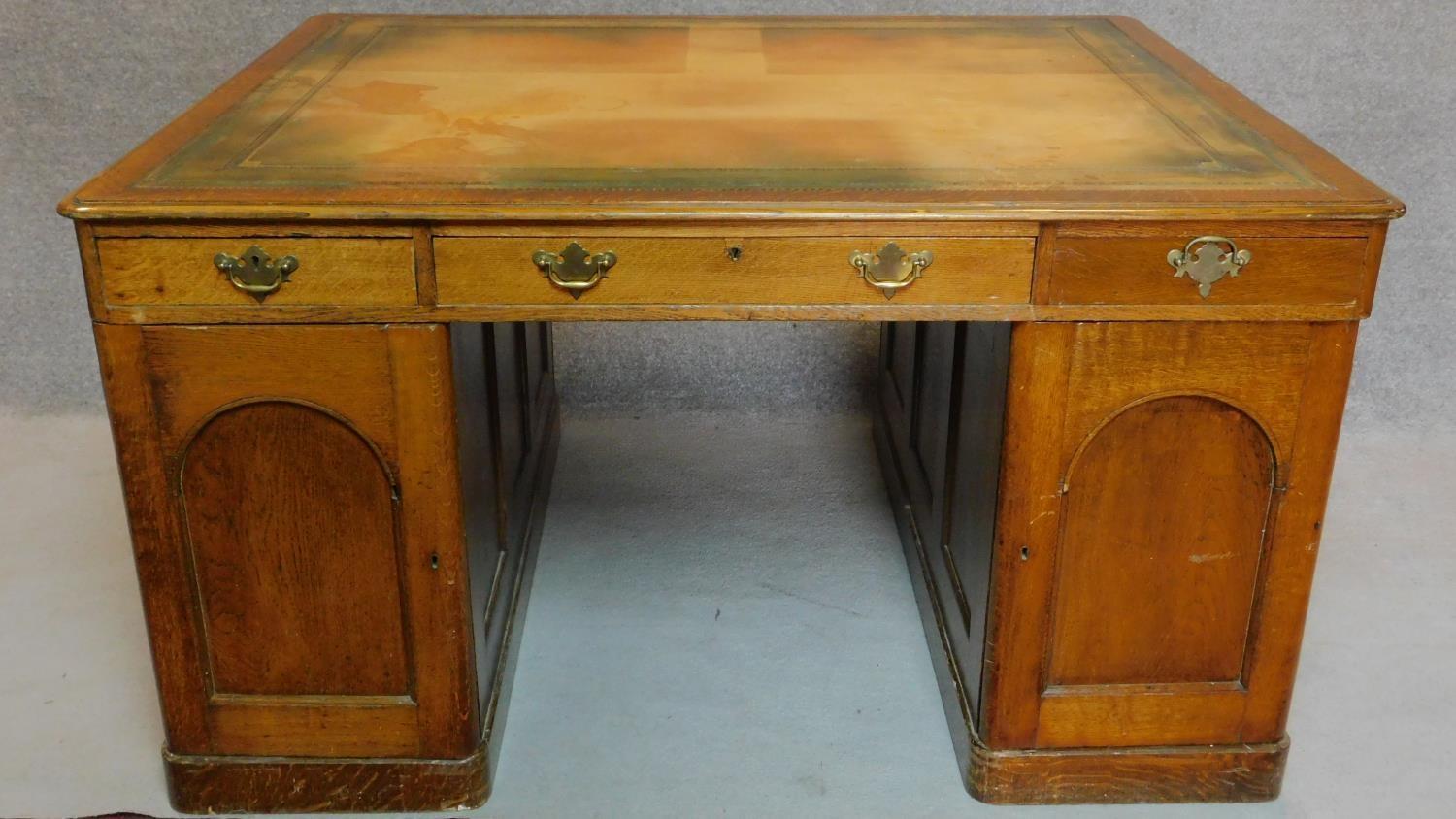 A Victorian oak partners desk with original tooled leather top above frieze drawers and pedestal