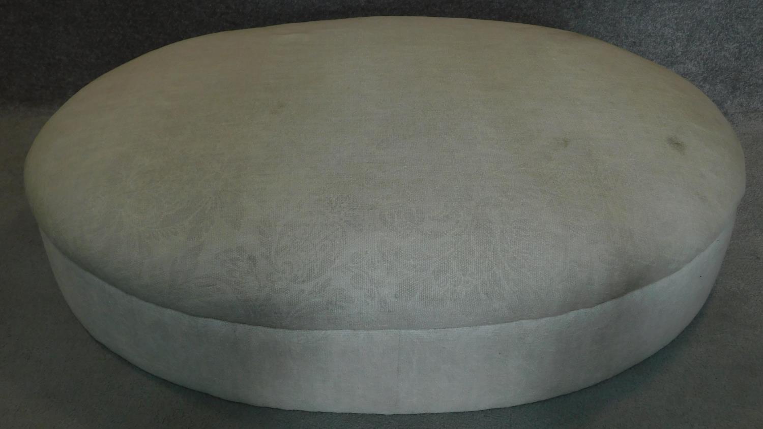 A large oval upholstered ottoman. H.27 W.123 D.95cm