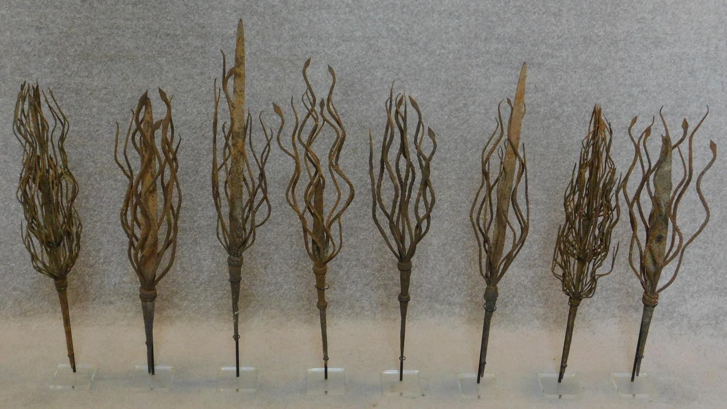 A set of eight decorative wrought metal foliate stands. H.80cm (tallest)