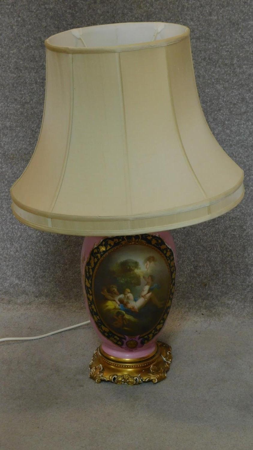 A large porcelain lamp base of bulbous form with rose pink background and hand painted cartouche