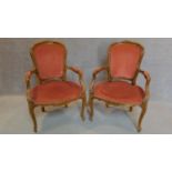 A pair of French carved beech framed open armchairs in blush upholstery on cabriole supports. H.96cm